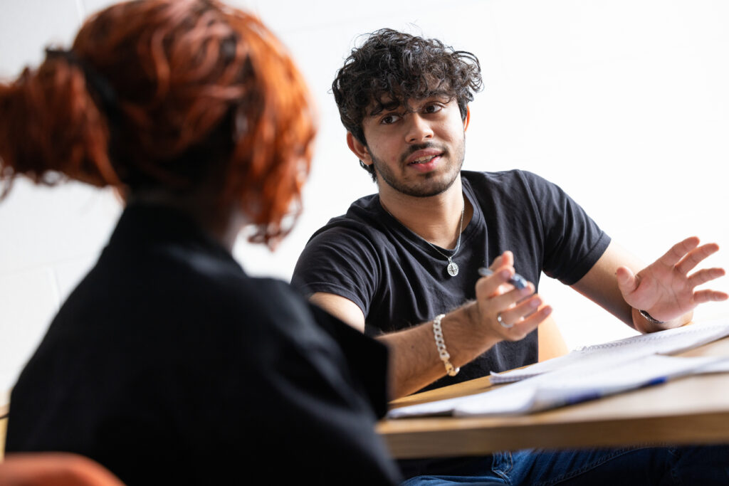 Multiethnic group of students studying together in a residence hall common area on a college campus.